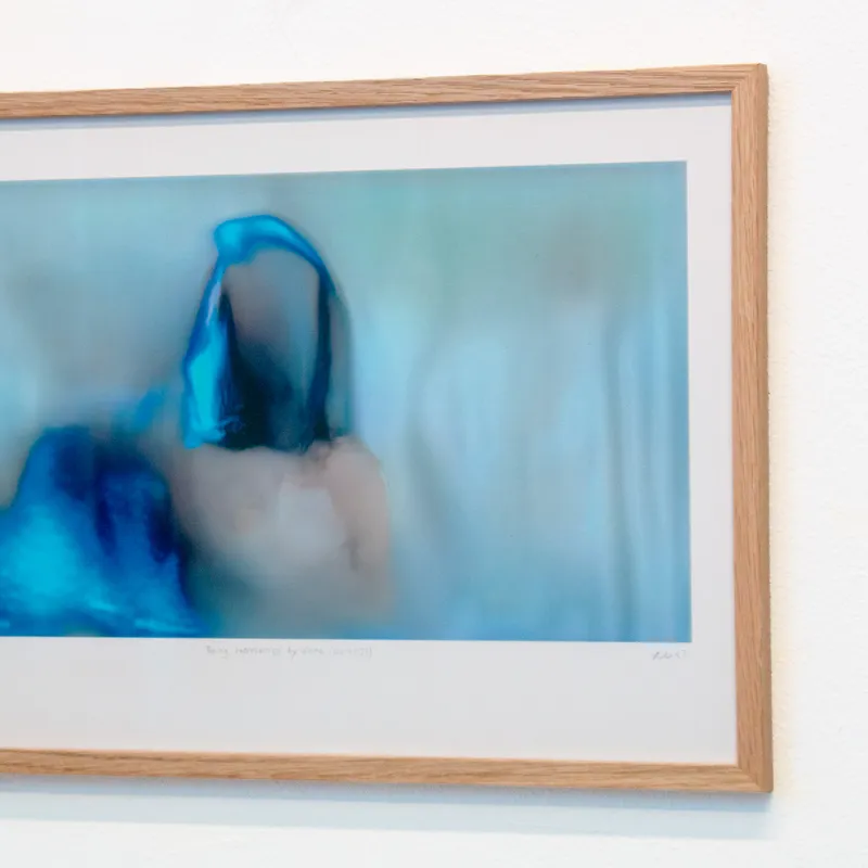 A sideways look at a framed version of a blue, glitchy still of "Being represented by data is like losing a part of yourself"